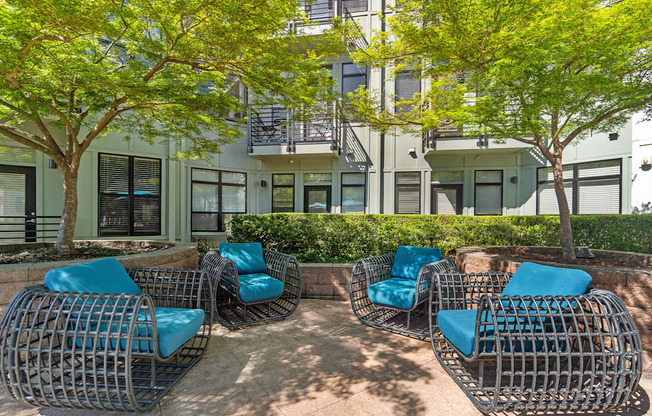 Four blue chairs are arranged in a circle on a patio.