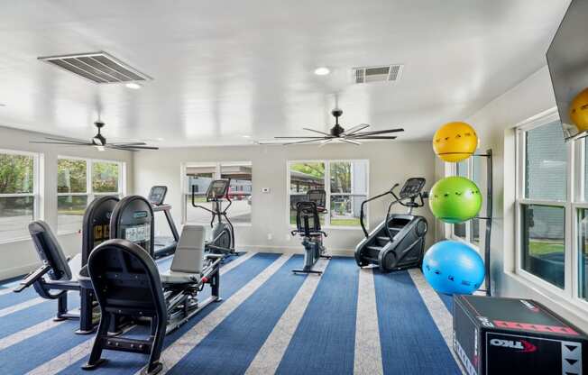 a gym with treadmills and other exercise equipment in a room with windows