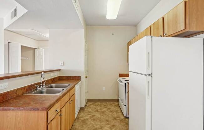 A kitchen with a white refrigerator and brown countertops.