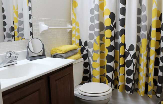 a bathroom with a black and yellow shower curtain and a toilet