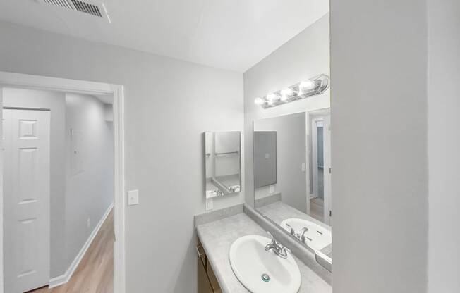 a bathroom with a sink and a mirror and a door