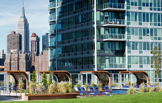 Apartment complex rooftop terrace with cabanas and sunchairs with views of the Empire State Building