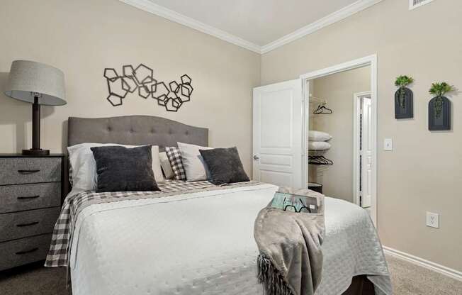 Windsor bedroom with a bed, closet, and wall decor at Encore at Buckingham Apartments in Richardson, TX