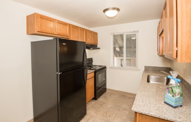 Todd Village vacant apartment kitchen with black appliances and wood cabinets