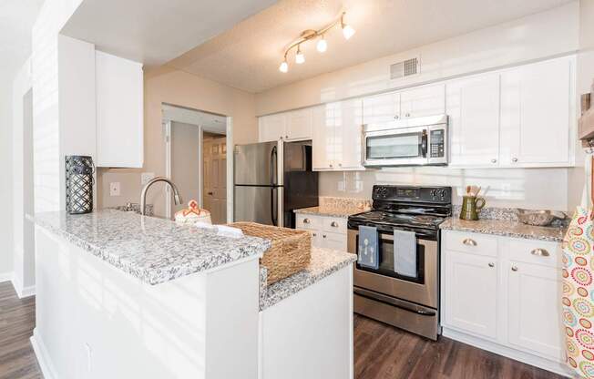 A kitchen with white cabinets and a granite countertop.