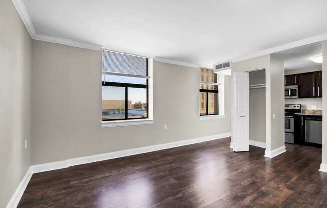 an empty living room with a window and a kitchen