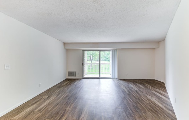 the spacious living room with wood flooring and a sliding glass door