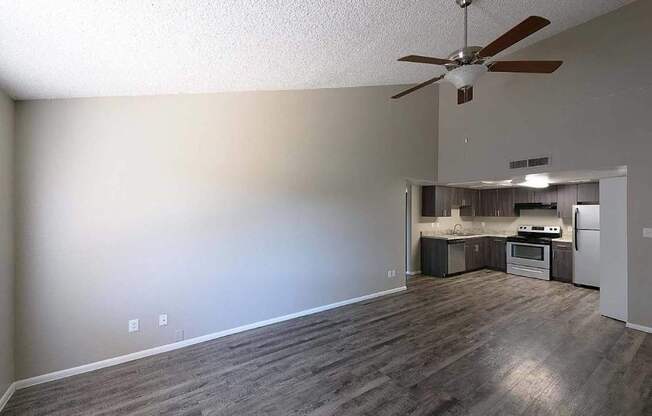 A room with a ceiling fan and a kitchenette.