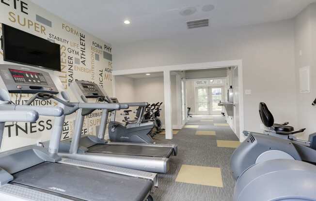 a gym with cardio equipment and a wall of black and white graffiti