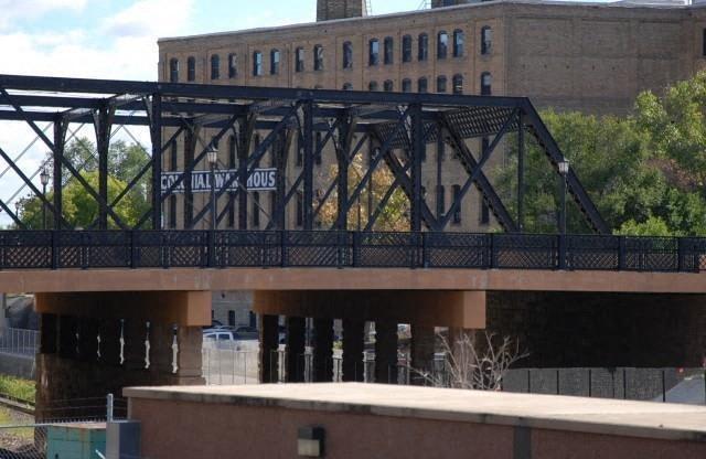 A bridge with a metal railing and a sign that says "HAL W. AOUS".
