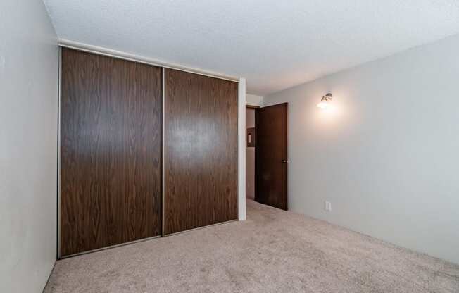 an empty bedroom with a wardrobe and an open door