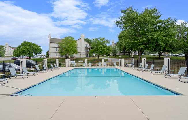 a swimming pool with chaise lounge chairs and trees in the background at Millcreek Woods Apartments, Kansas, 66061