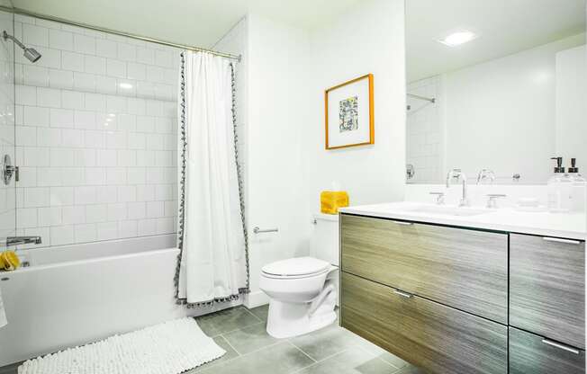 A bathroom with a white toilet, a white shower curtain, and a white rug.