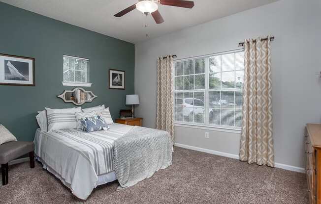 A bedroom with a bed, nightstand, and window.