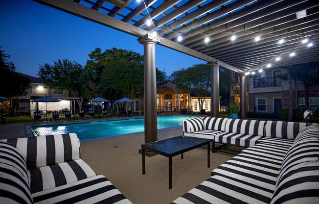 Affordable Houston Texas Apartments – Westchase Forest – Photo of a swimming pool with black and white striped lounge chairs under a patio