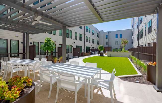 A patio with white chairs and tables is covered by a white roof.