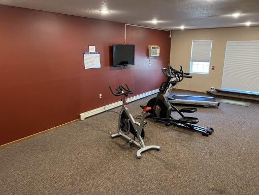 a room with two exercise bikes and a flat screen tv at Bluemont Village Apartments, Fargo, North Dakota