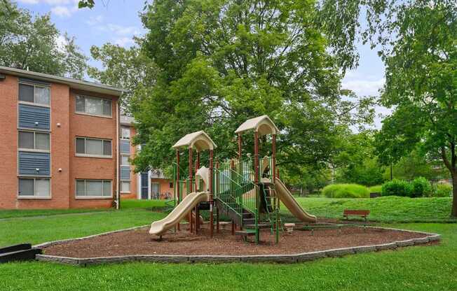 A playground with a slide and swings in a grassy area.
