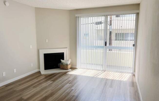 an empty living room with a fireplace and a sliding glass door