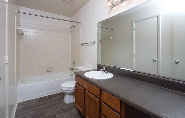 An empty bathroom with a white toilet, sink, and bathtub.