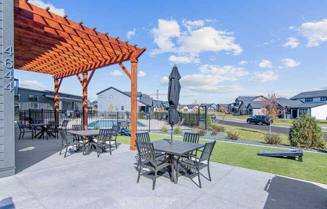 a patio with a pergola and tables with umbrellas