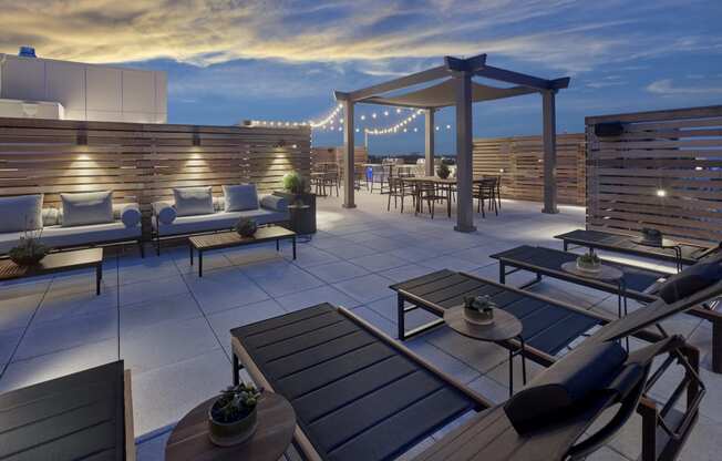 Luxurious rooftop lounge at night at The Mint Rahway, with comfortable seating, pergolas, and string lights, providing a serene atmosphere.