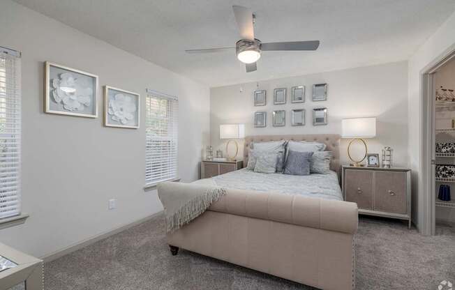 A bedroom with a bed, nightstands, and pictures on the wall.