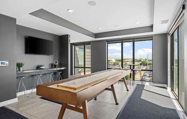 A modern kitchen with a long wooden table and a flat screen TV mounted on the wall.