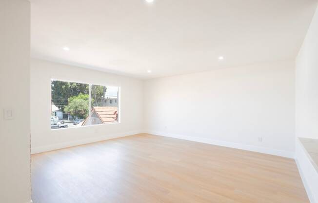 an empty living room with a window and wooden floors