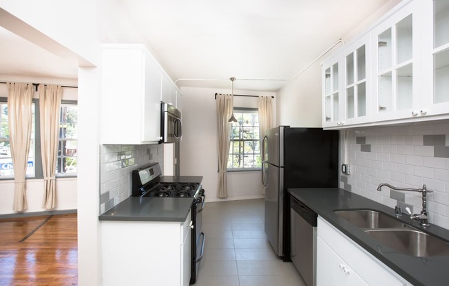 a kitchen with black counter tops and white cabinets at Del Mor, Los Angeles, CA, 90026