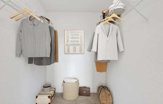 a walk in closet with white walls and wooden clothes hangers