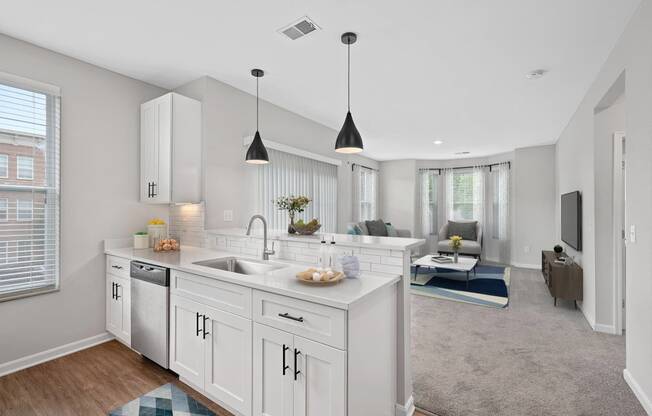 an open kitchen and living room with white cabinets and a white counter top