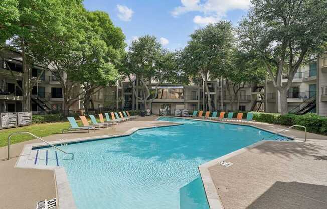 A swimming pool surrounded by trees and chairs.