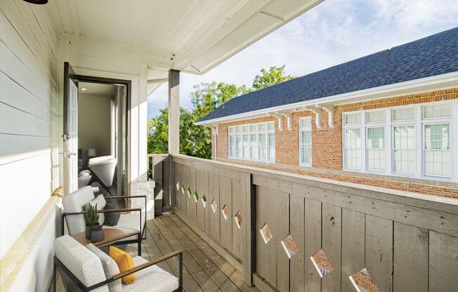 a balcony with a couch and chairs and a brick building