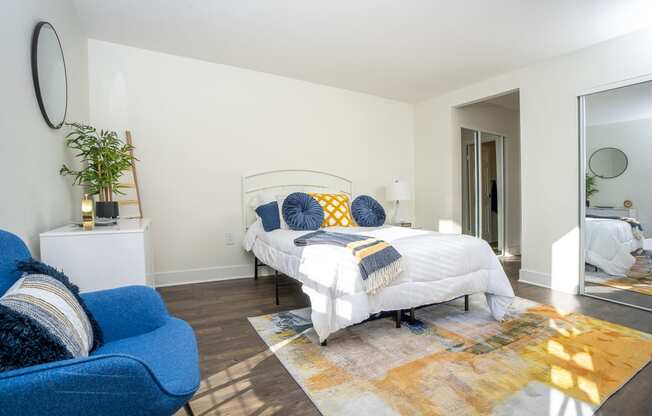 Bedroom wtih bed, blue chair, a large rug and mirror on the wall at Vera Cortez Hill, San Diego