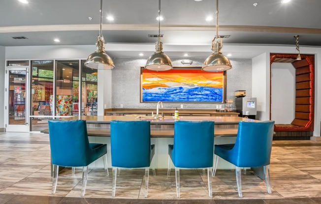a dining room with blue chairs and a table with a colorful painting at South Side Flats, Dallas, Texas