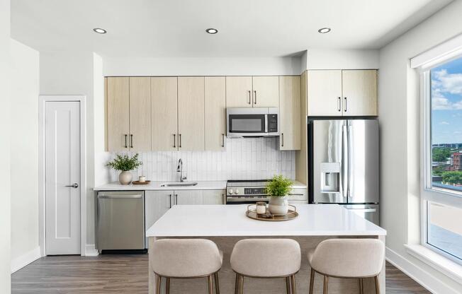 Bright kitchen with full-height cabinetry, quartz island seating, and large windows that bring in daylight and frame neighborhood views.
