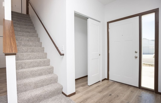 a staircase in a home with white walls and a door to a closet