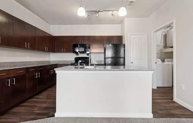 A kitchen with a white island and dark brown cabinets.