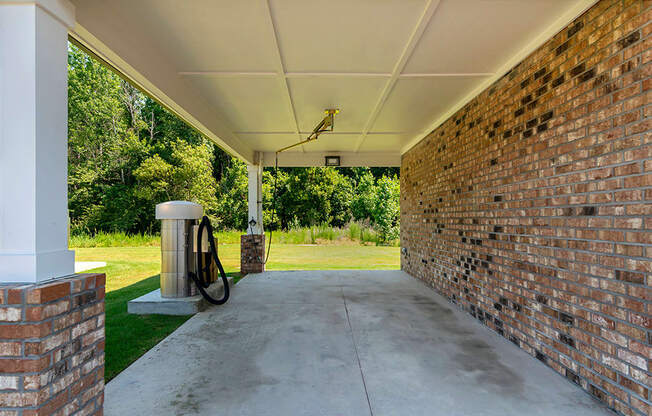 an empty porch with a brick wall and a trash can on it