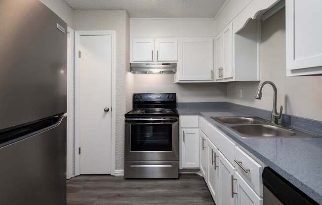 A kitchen with a refrigerator, oven, and sink.