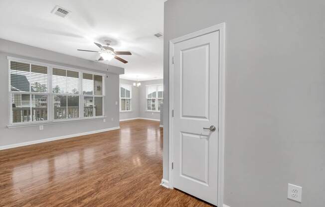 an empty living room with a white door and a ceiling fan