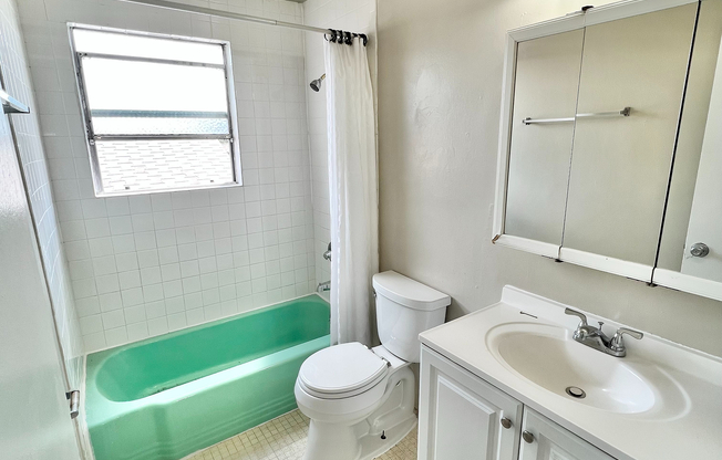 Bright and inviting bathroom with a retro green bathtub, elegant white tiles, and a modern vanity.