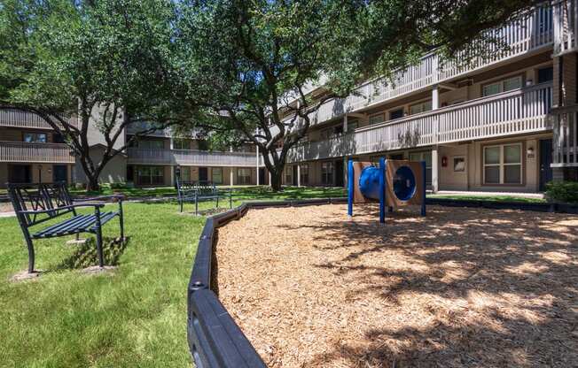 This is a photo of a couple of benches by the playground in the courtyard at Harvard Square Apartments, in the Vickery Meadow neighborhood of Dallas, TX.