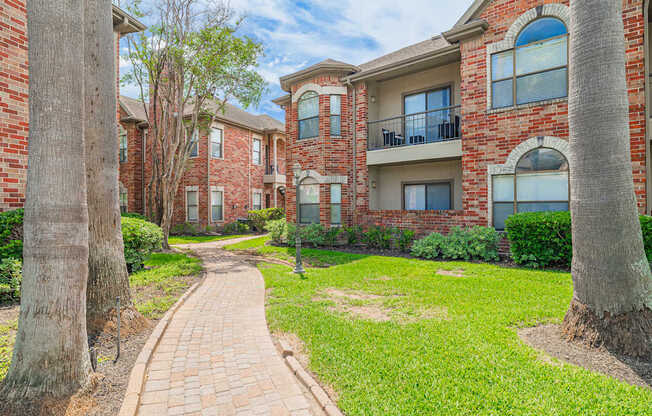 A brick pathway leads to a row of apartment buildings.