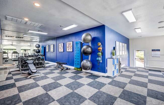 a spacious fitness center with a checkered floor and blue walls