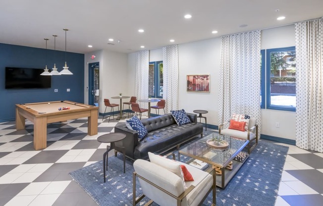 a living room with couches and a table with a pool table