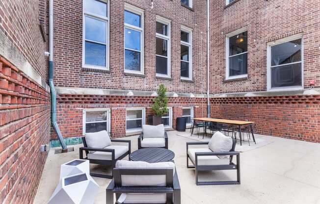 the patio of a brick building with chairs and a table