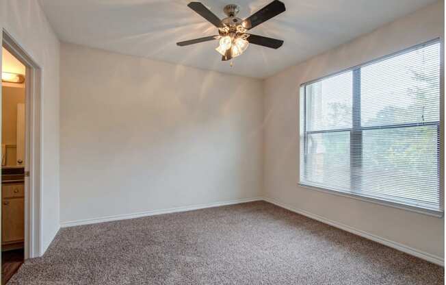 a bedroom with a large window and a ceiling fan