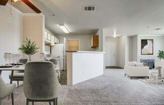 A modern living room with a grey carpet and a dining table set for two.